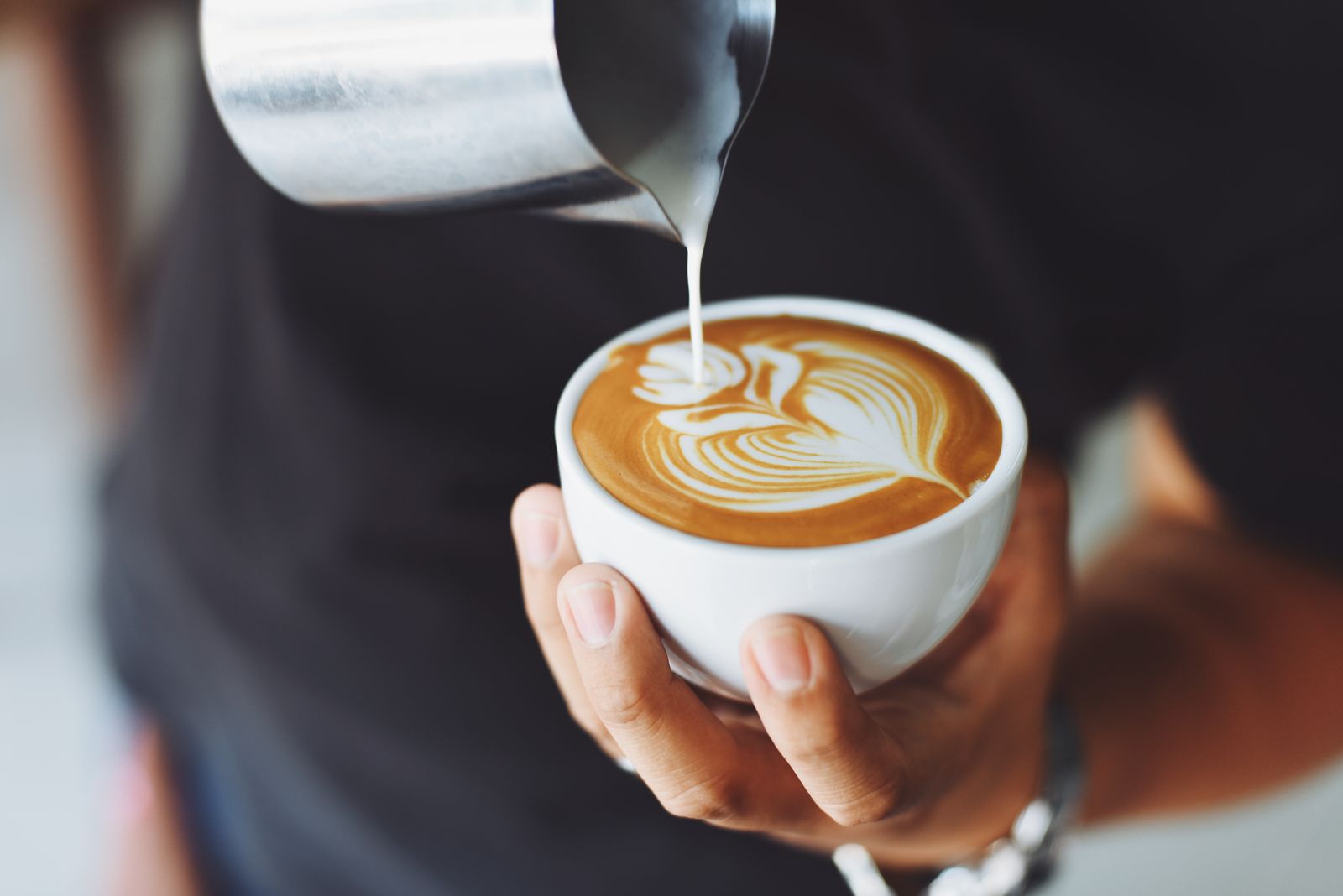 Barista pouring latte art behind the counter